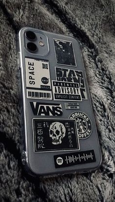 an iphone case with stickers on it sitting on a fur covered surface in black and white