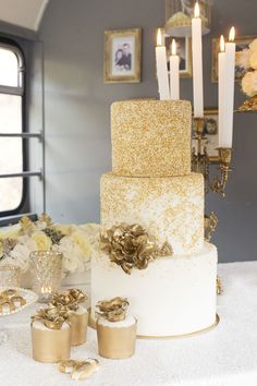 there is a wedding cake with gold decorations on the table and candles in the background