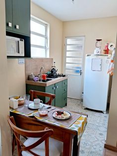 a small kitchen with a table, refrigerator and sink in it's center area