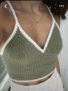 a woman wearing a green and white crochet crop top with her hands in her pockets