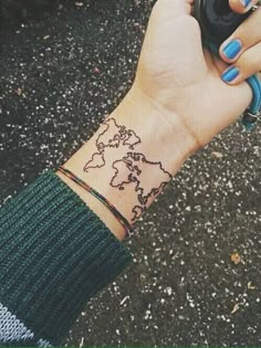 a woman's wrist with a world map tattoo on it