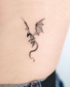 a small dragon tattoo on the back of a woman's stomach