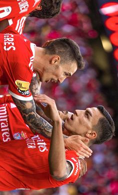 two men in red jerseys are playing soccer