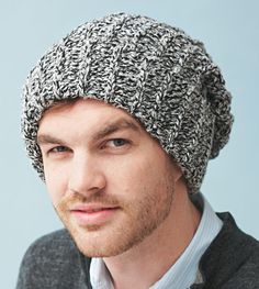 a young man wearing a knitted hat looks at the camera