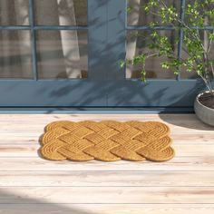 a door mat sitting on top of a wooden floor next to a potted plant