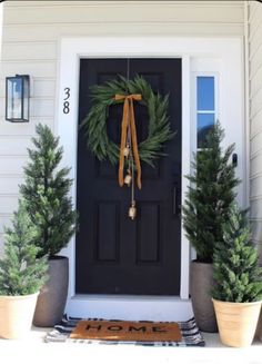 the front door is decorated with evergreen wreaths