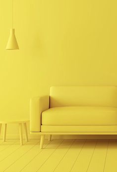 a yellow room with a white couch and two stools in front of the wall