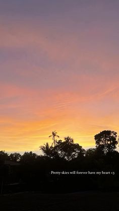 the sky is pink and orange as the sun sets over some trees in the distance