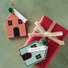 two presents wrapped in red and green paper with tags attached to them, sitting next to each other