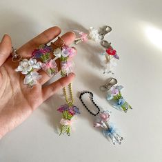 a hand is holding several different types of keychains and charms on a white surface