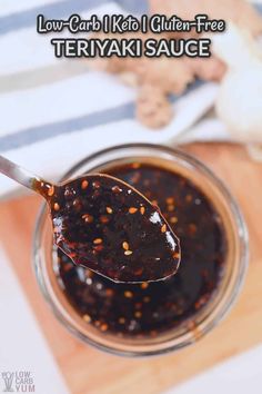 a spoon full of teriyaki sauce sitting on top of a wooden cutting board