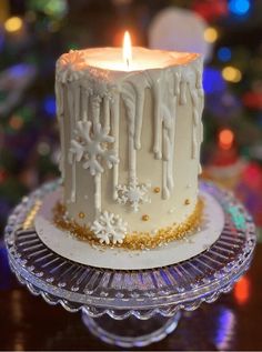 a white frosted cake sitting on top of a glass plate next to a lit candle