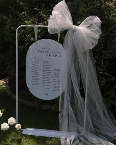 a sign that is sitting in the grass next to some white flowers and netting on it