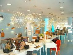 the inside of a women's clothing store with many purses and handbags on display