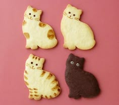 four cookies shaped like cats sitting next to each other on a pink surface with white and brown icing