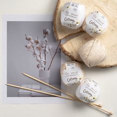 three balls of yarn sitting on top of a piece of wood next to knitting needles