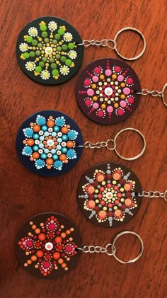 four key chains with different designs on them sitting on a wooden table next to each other