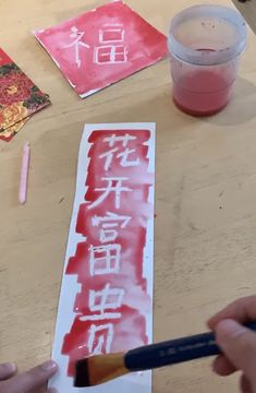 someone is painting chinese characters on paper