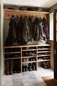 an open closet with shoes and coats hanging on the wall