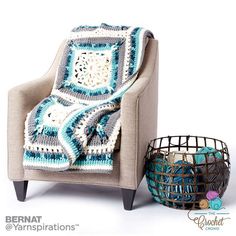 a crocheted afghan sitting on top of a chair next to a basket filled with yarn