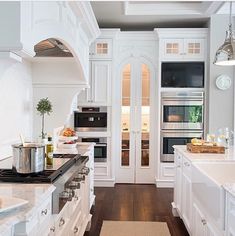 a kitchen with white cabinets and an oven in the center is seen from across the room