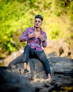 a young man sitting on top of a rock