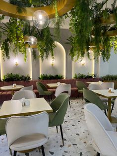 the interior of a restaurant with plants hanging from the ceiling and tables set up for dinner