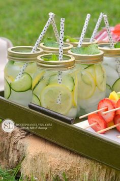 mason jars filled with pickles, lemons and strawberries on a picnic table