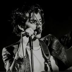 black and white photograph of a man singing into a microphone with his hands in the air