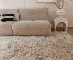 a beige couch sitting on top of a white rug