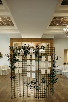 a room divider with lots of cards attached to it and greenery growing on the wall