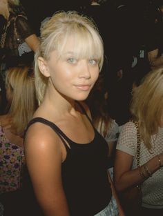 a woman with blonde hair and blue eyes standing next to other women at a party