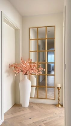 a vase with some flowers in it sitting on a wooden floor next to a mirror