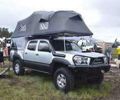 a truck with a tent on it parked in the grass