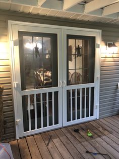 two glass doors on the outside of a house with wood flooring and metal siding