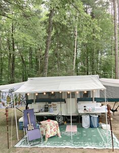 an rv parked in the woods with its awning open and camping equipment set up