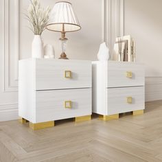 two white dressers with gold handles on them in an empty room, next to a lamp