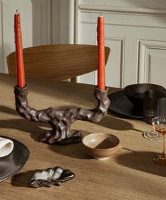 a wooden table topped with plates and candles