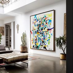 a living room filled with furniture and paintings on the wall next to potted plants