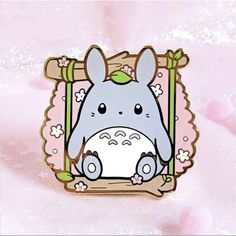 a pin with an image of a totoro sitting in front of a pink background