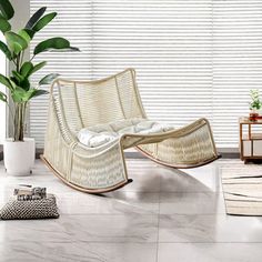 a living room filled with furniture next to a window covered in white blinds and plants