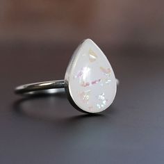 "Breastmilk jewelry teardrop 14x10mm stone sterling silver ring. Opal effect flakes can be added. To see our full breastmilk Ring collection, please click here: https://www.etsy.com/ca/shop/KeepsakeMom?ref=simple-shop-header-name&listing_id=1095328032&section_id=24695275 To see All our items, please click here: https://www.etsy.com/ca/shop/KeepsakeMom?ref=simple-shop-header-name&listing_id=1095328032 BREASTMILK JEWELRY NOTICE: For jewelry made with your own breast milk, please visit www.Keepsake White Jewelry With Birthstone For Keepsake, White Birthstone Jewelry For Keepsake, White Keepsake Jewelry With Birthstone, White Hypoallergenic Opal Jewelry, Hypoallergenic White Opal Jewelry, White Oval Jewelry With Natural Inclusions, Personalized White Teardrop Jewelry, Oval White Jewelry With Natural Inclusions, White Hypoallergenic Teardrop Jewelry