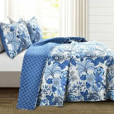 a bed covered in blue and white floral bedspread