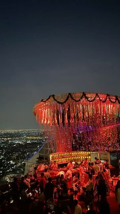 an aerial view of the city at night with lights on and people sitting in chairs