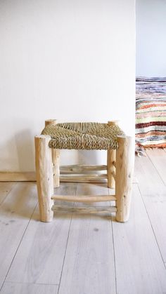 a wooden bench sitting on top of a hard wood floor next to a white wall