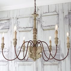 a chandelier hanging from the ceiling in front of wooden paneled walls and doors