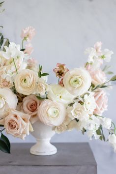 a white vase filled with lots of pink and white flowers