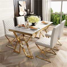 a dining room table set with white chairs and gold trimmings on the legs