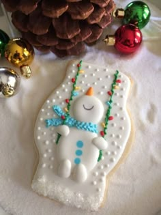 a decorated cookie sitting on top of a table next to christmas ornaments and pine cones