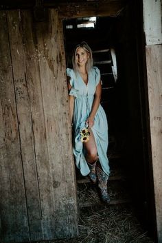 a woman in a blue dress is standing on some stairs